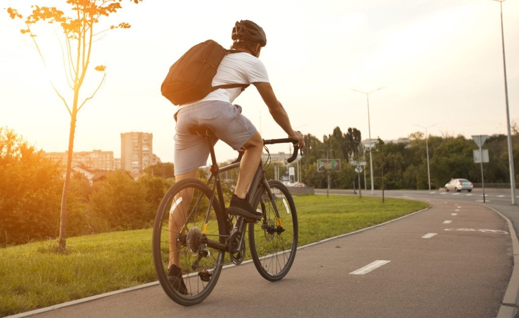 Un tipo con ropa informal va en bicicleta por la carretera por la noche.